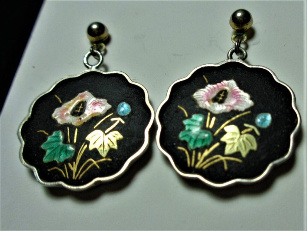 Scalloped round earrings, black background, inlaid pink flower