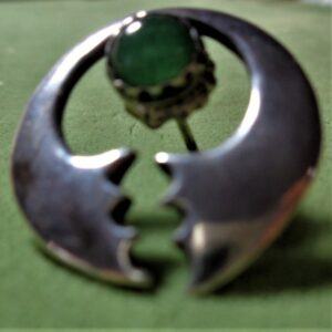 Green circle, open at bottom with jagged edge, green stone set under circle